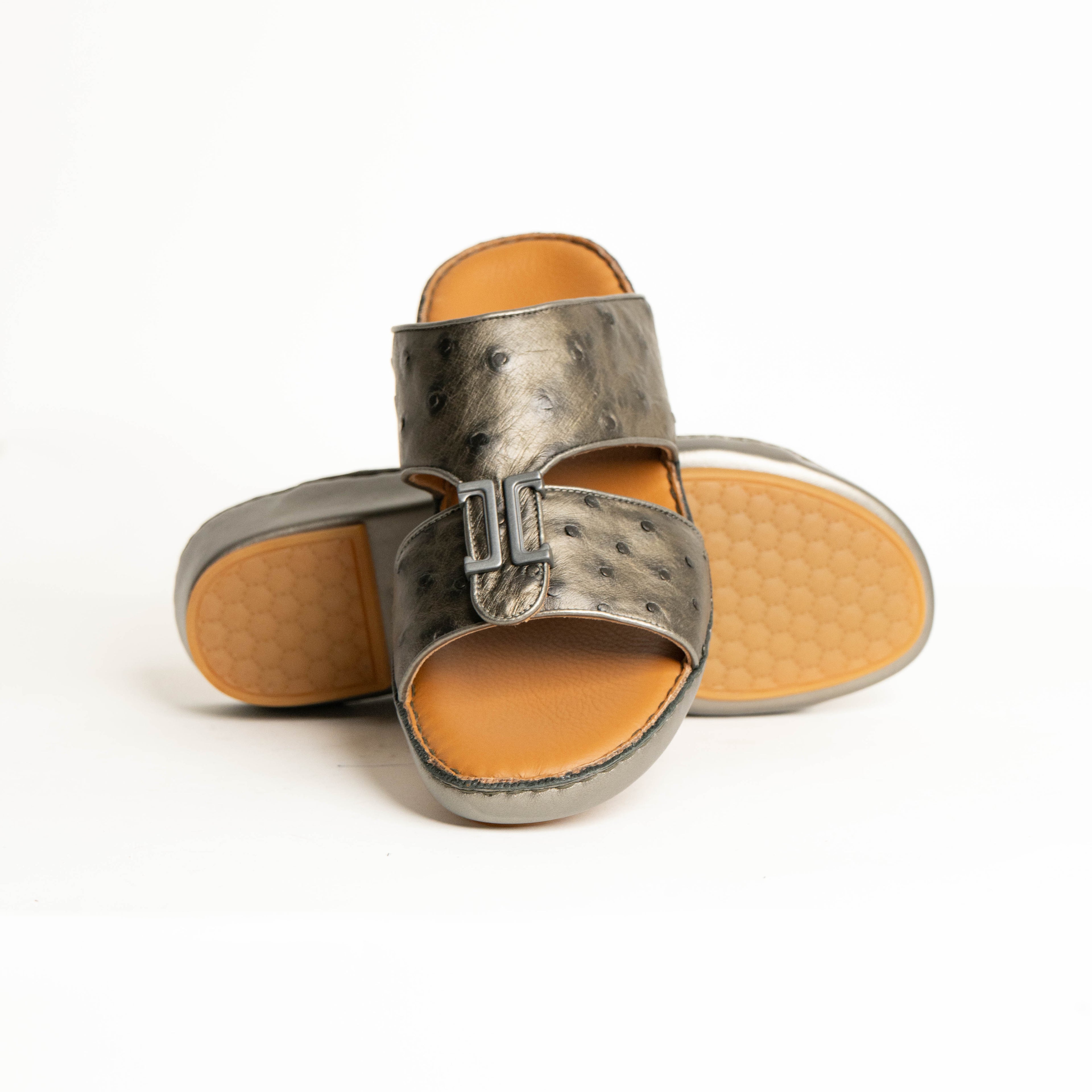 Pair of metallic sandals with tan soles on a white background