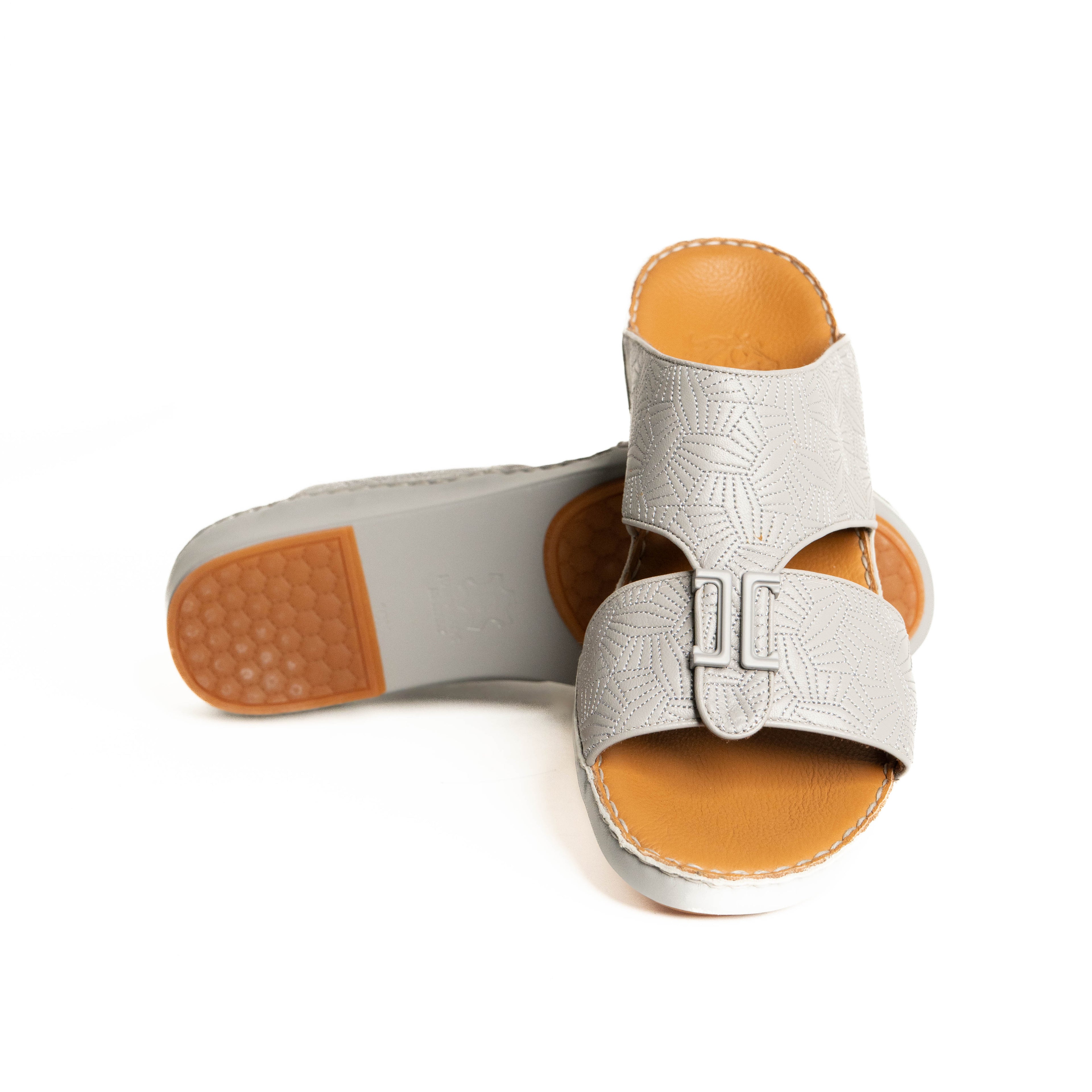 Pair of silver sandals with brown soles on a white background