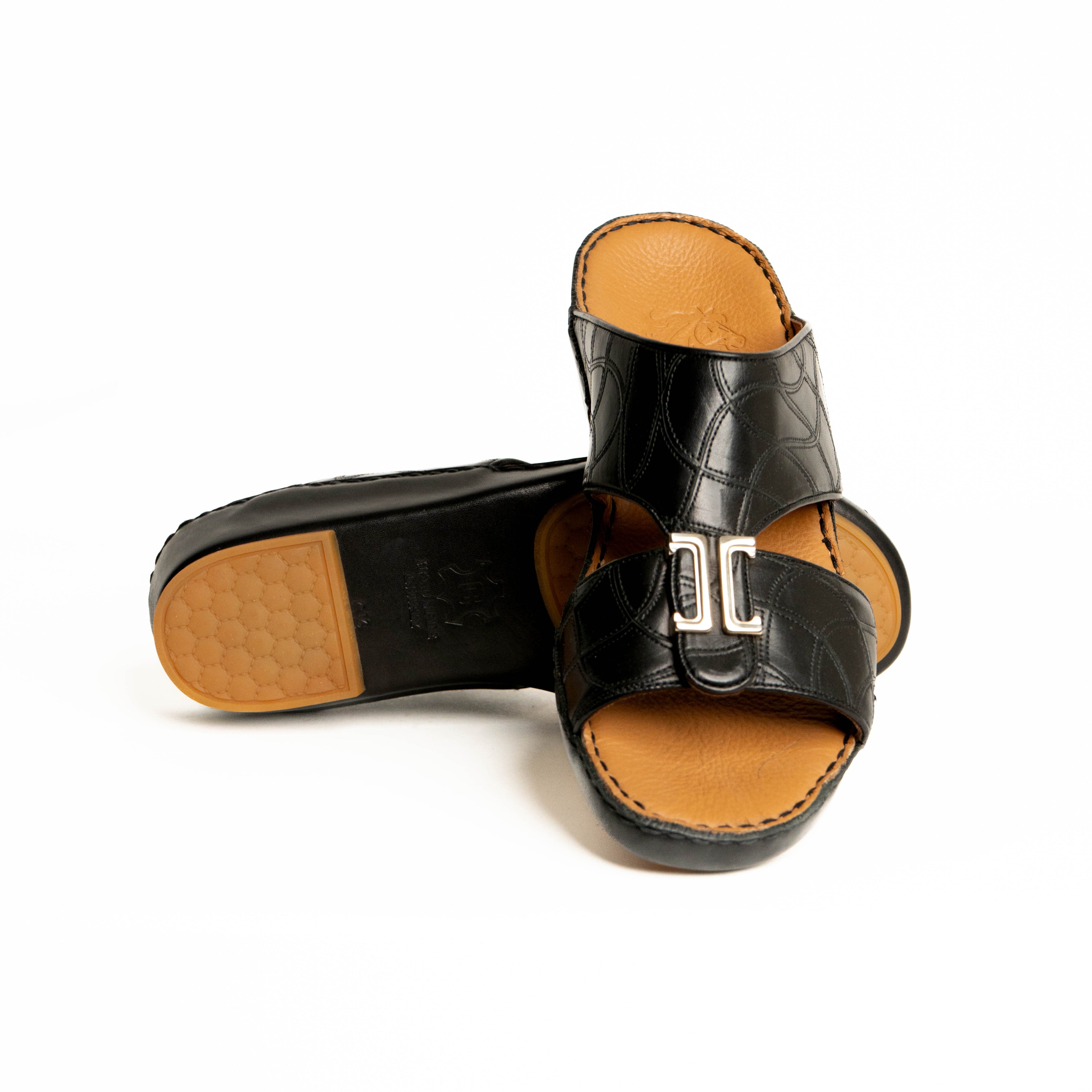Black sandals with tan soles on a white background