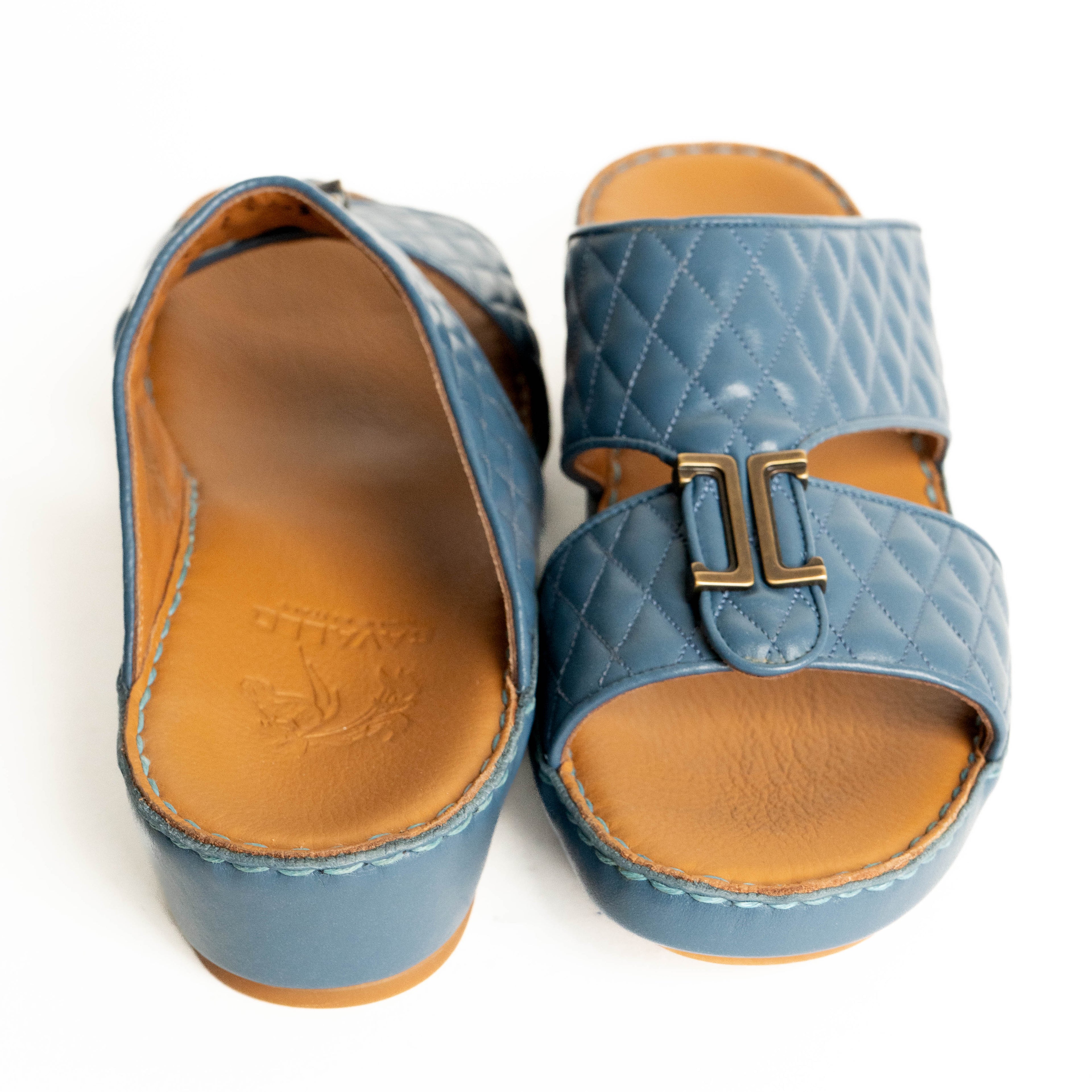 Pair of blue quilted sandals with brown soles on a white background