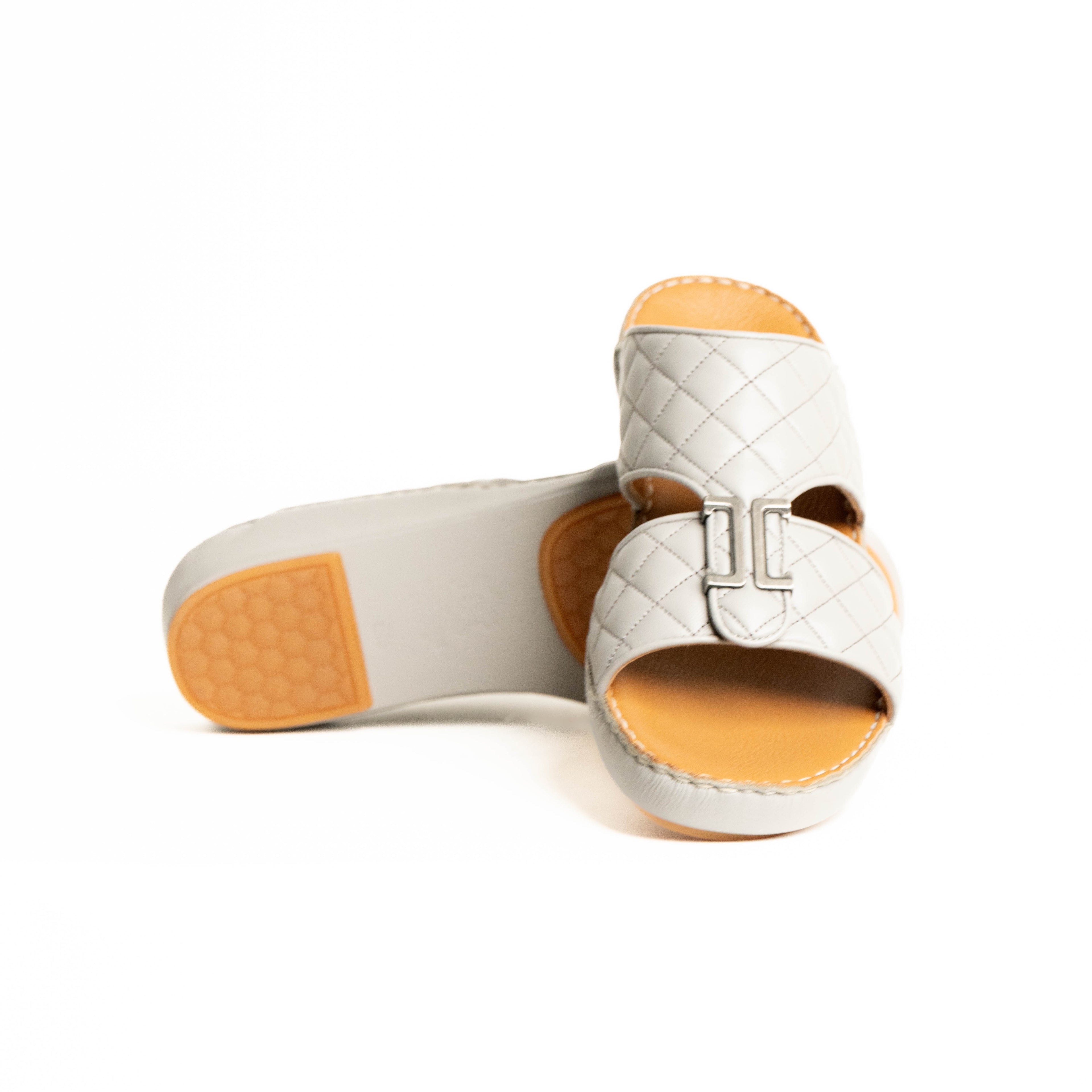 White quilted sandal with orange soles on a white background