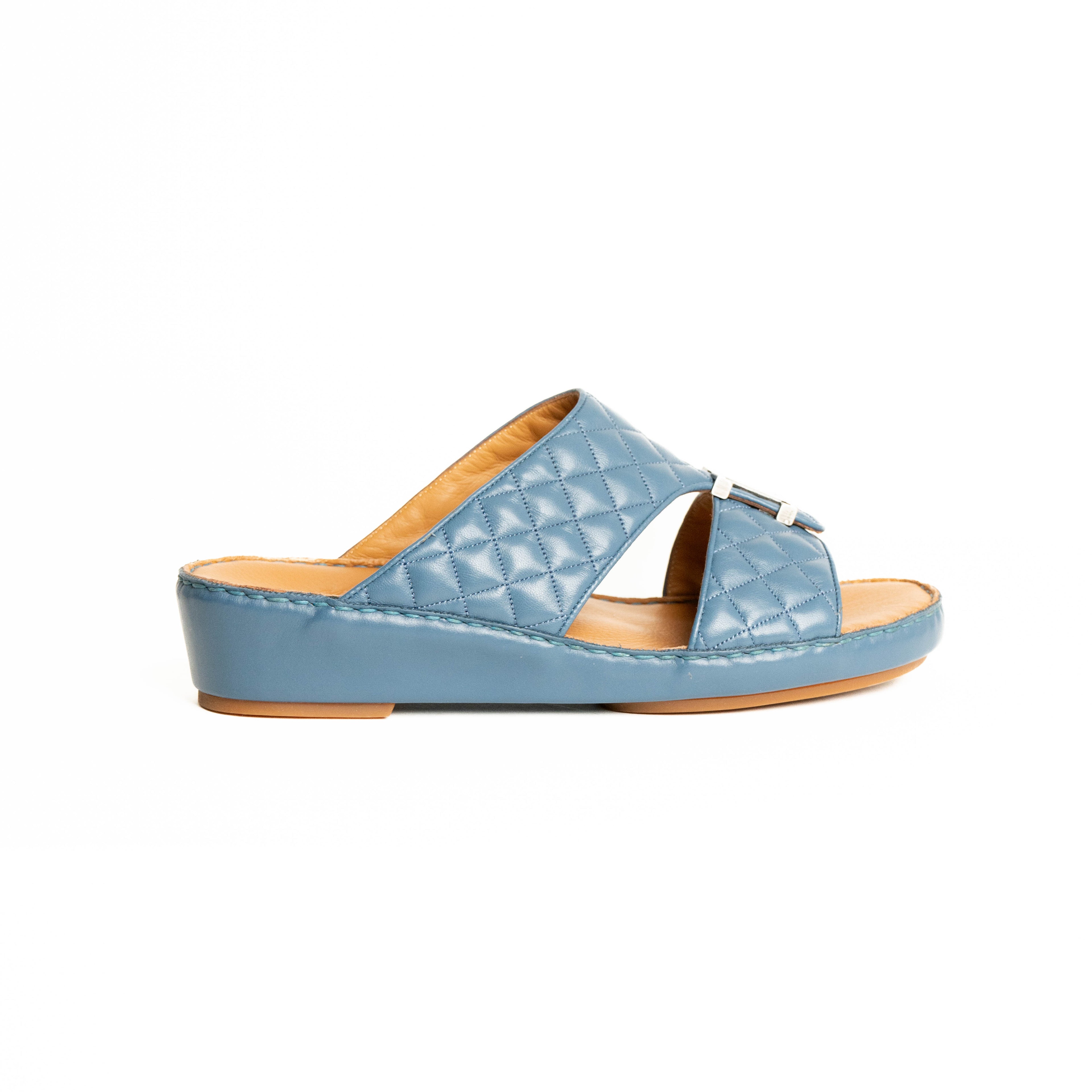 Blue quilted sandal with a brown insole on a white background