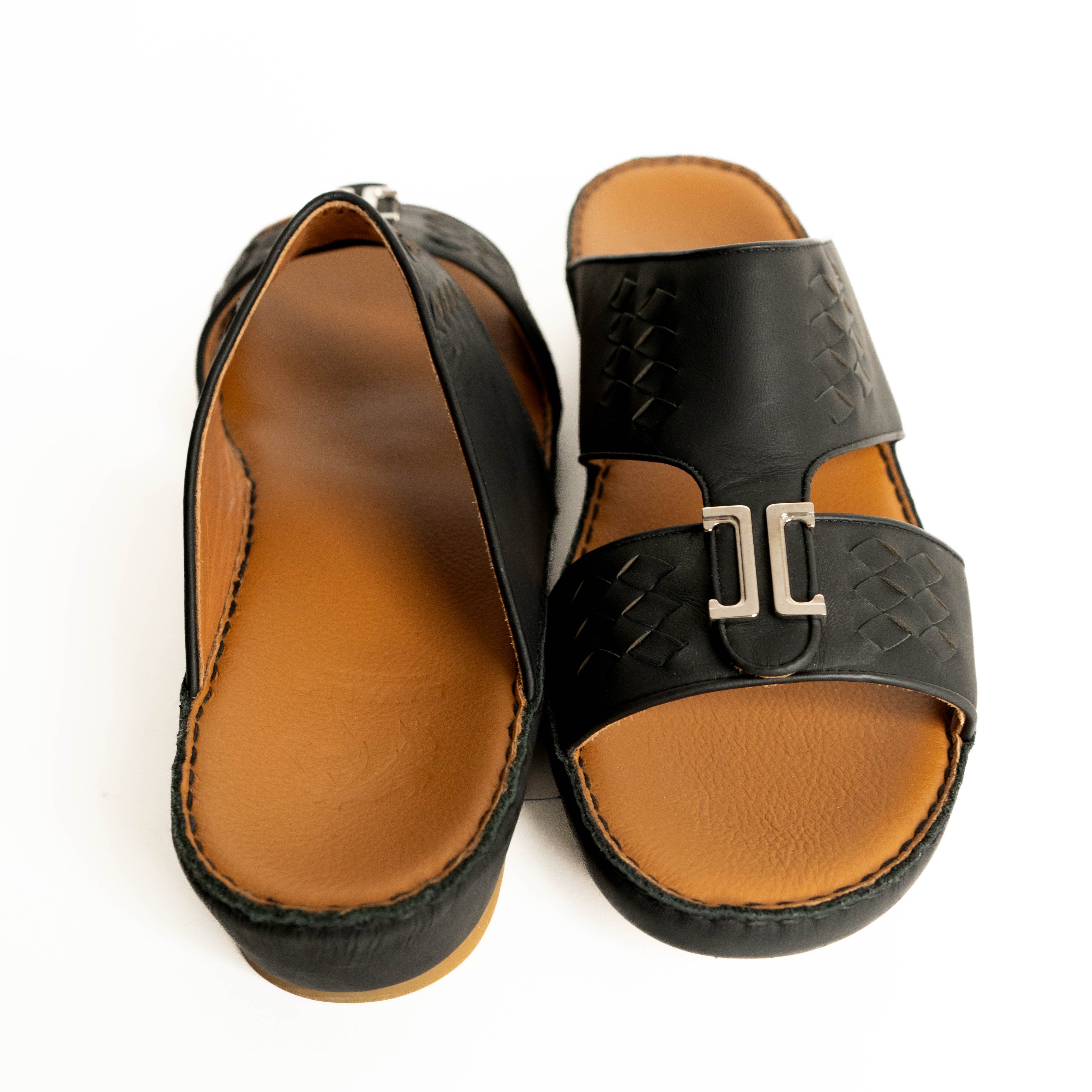 Pair of black sandals with brown soles on a white background