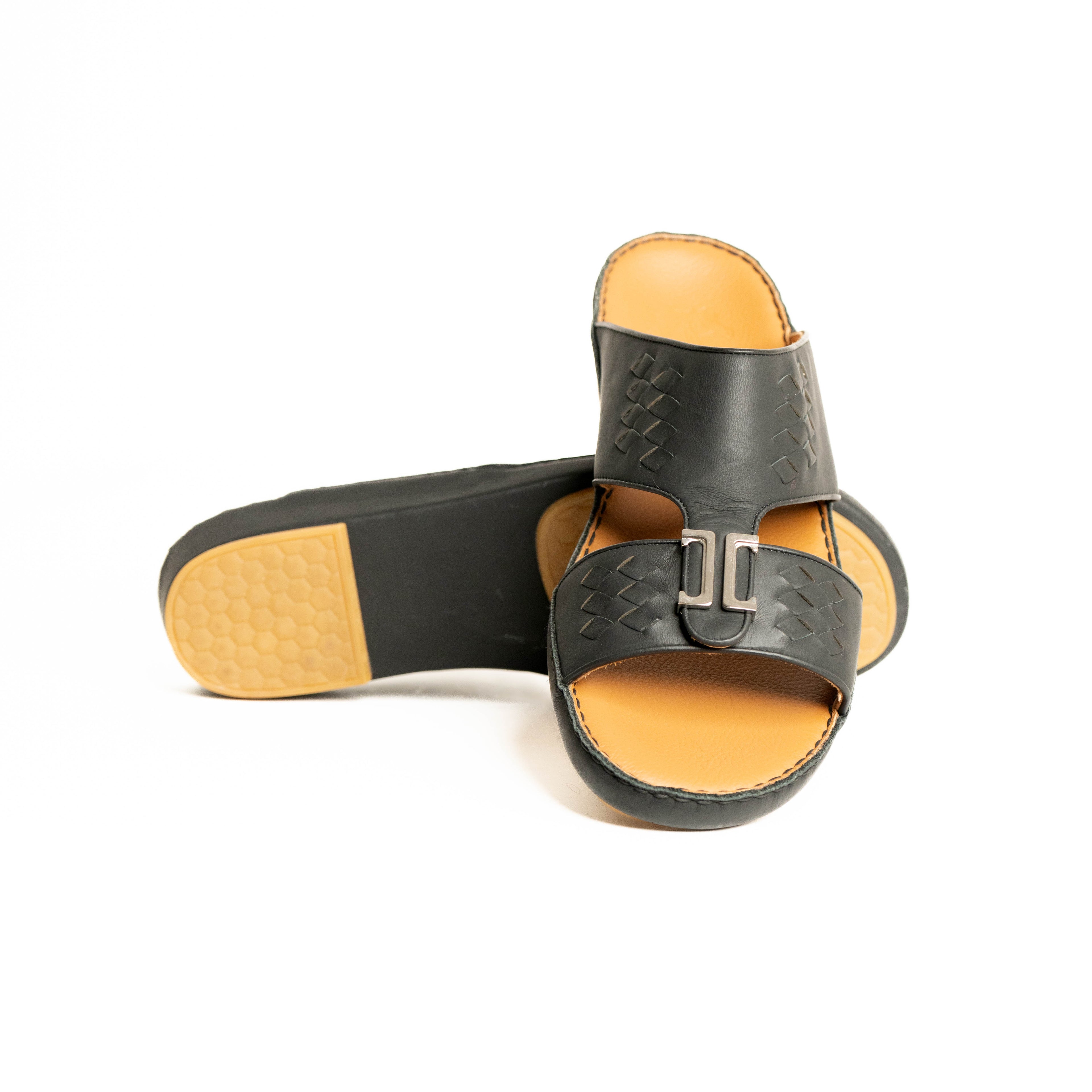 Pair of black sandals with tan soles on a white background