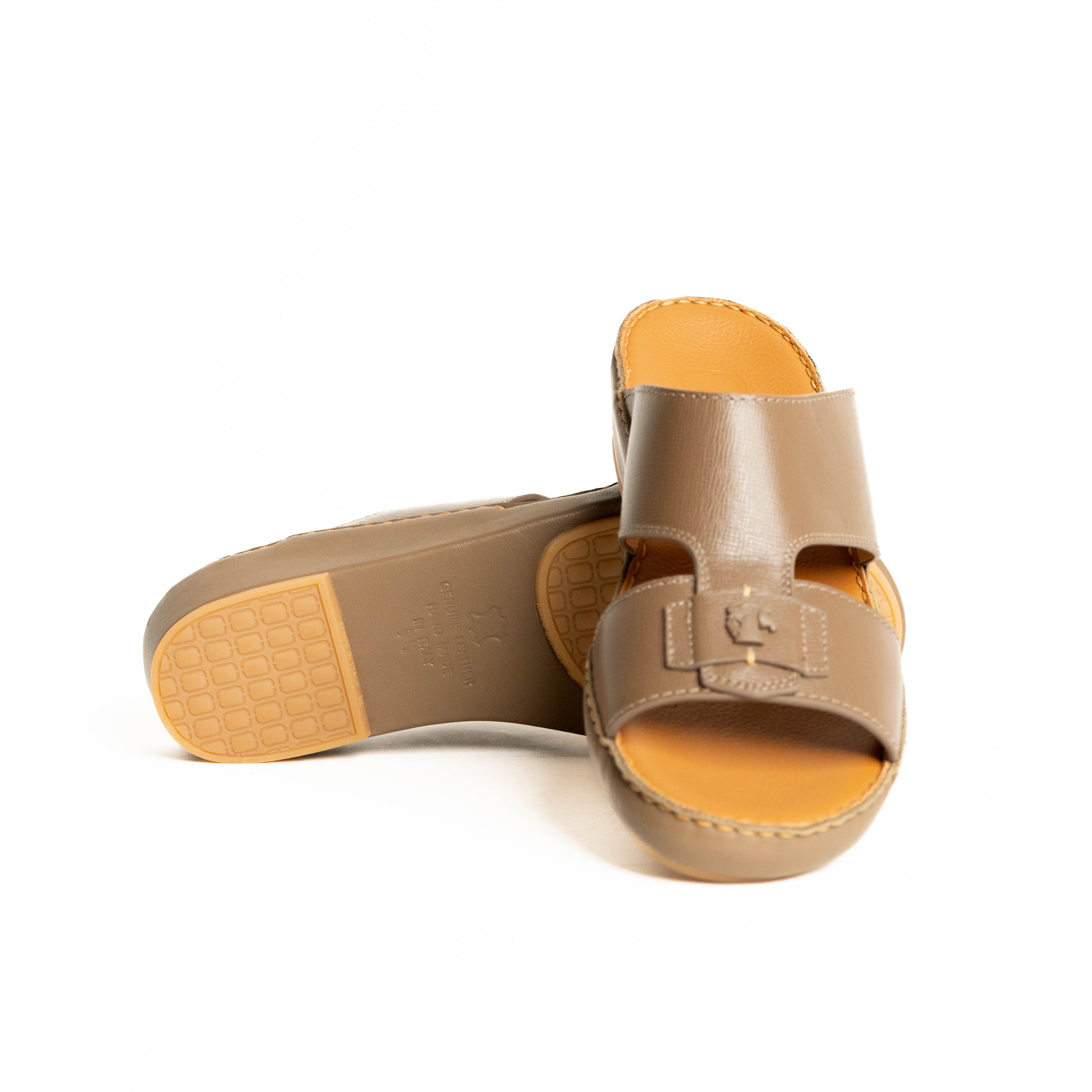 Pair of tan sandals with yellow soles on a white background