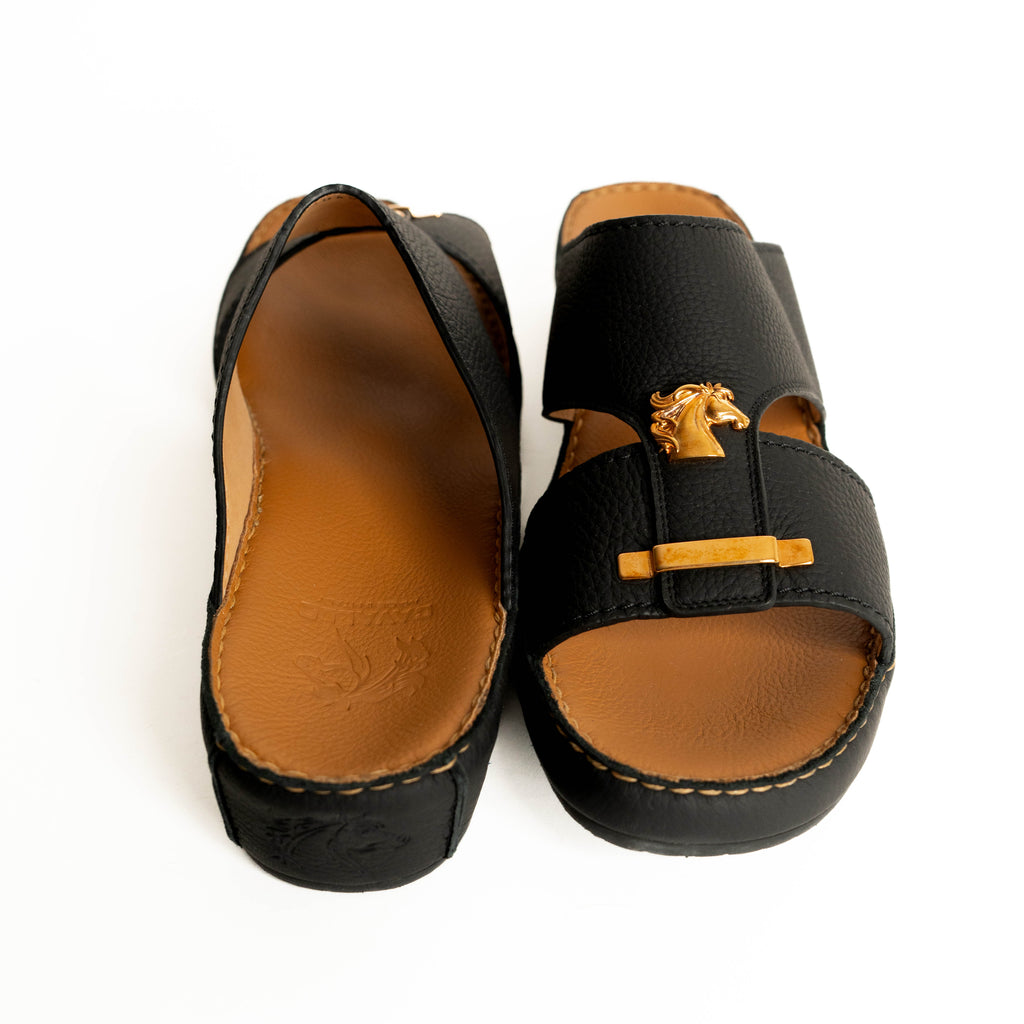 Pair of black sandals with brown soles on a white background