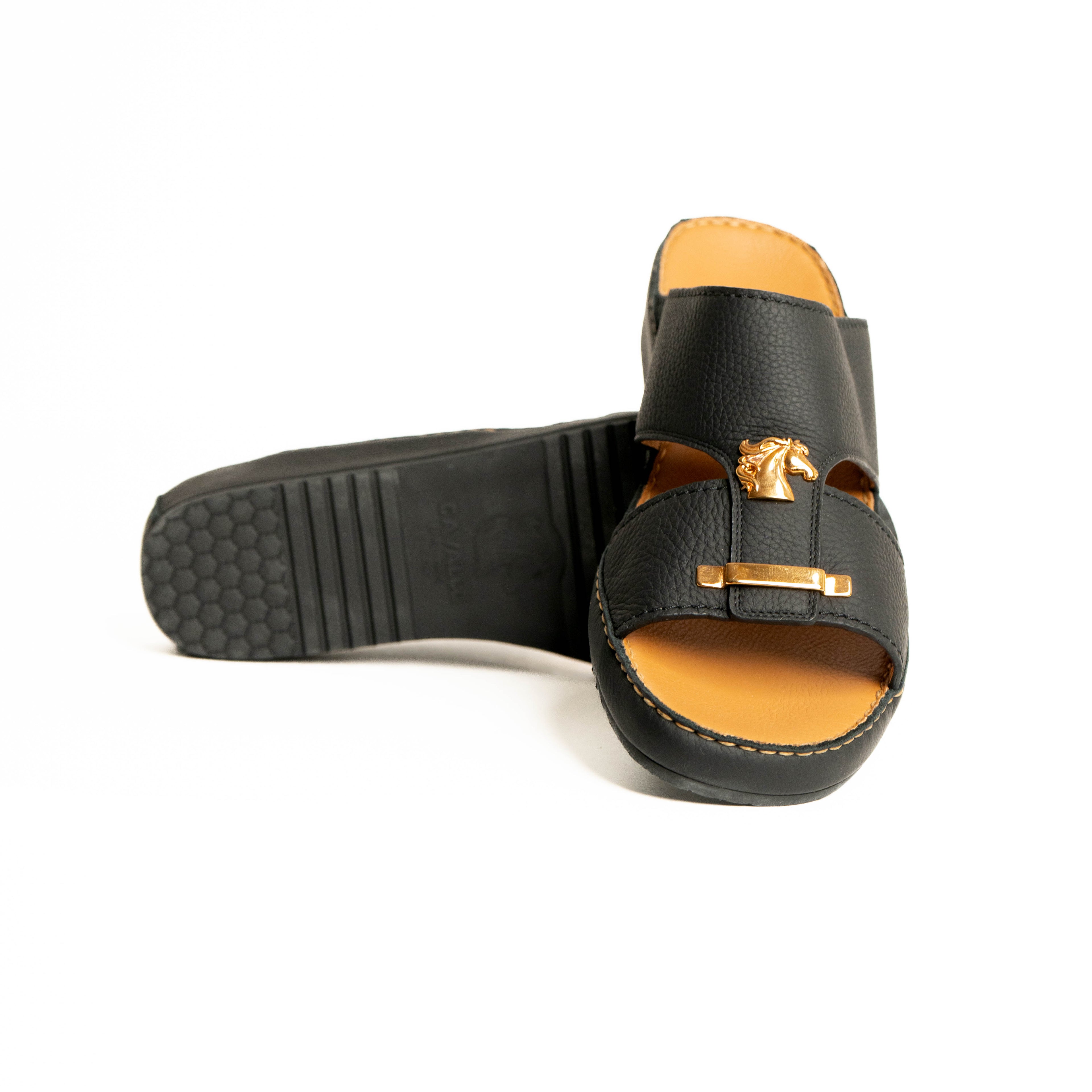 Black sandal with gold buckle on a white background