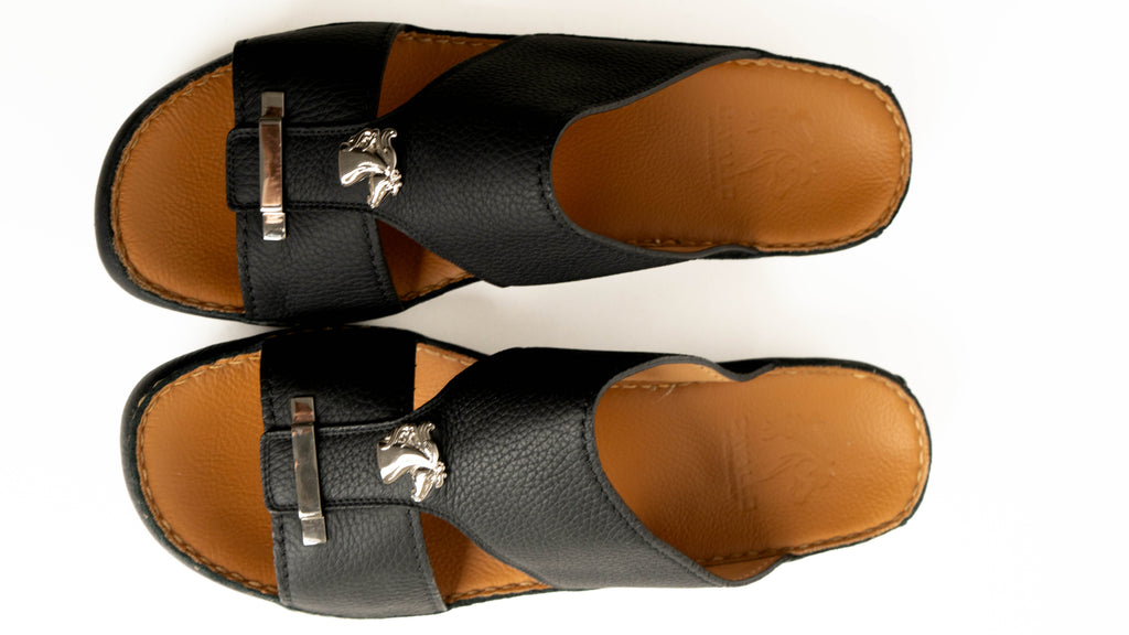 Pair of black sandals with brown soles on a white background