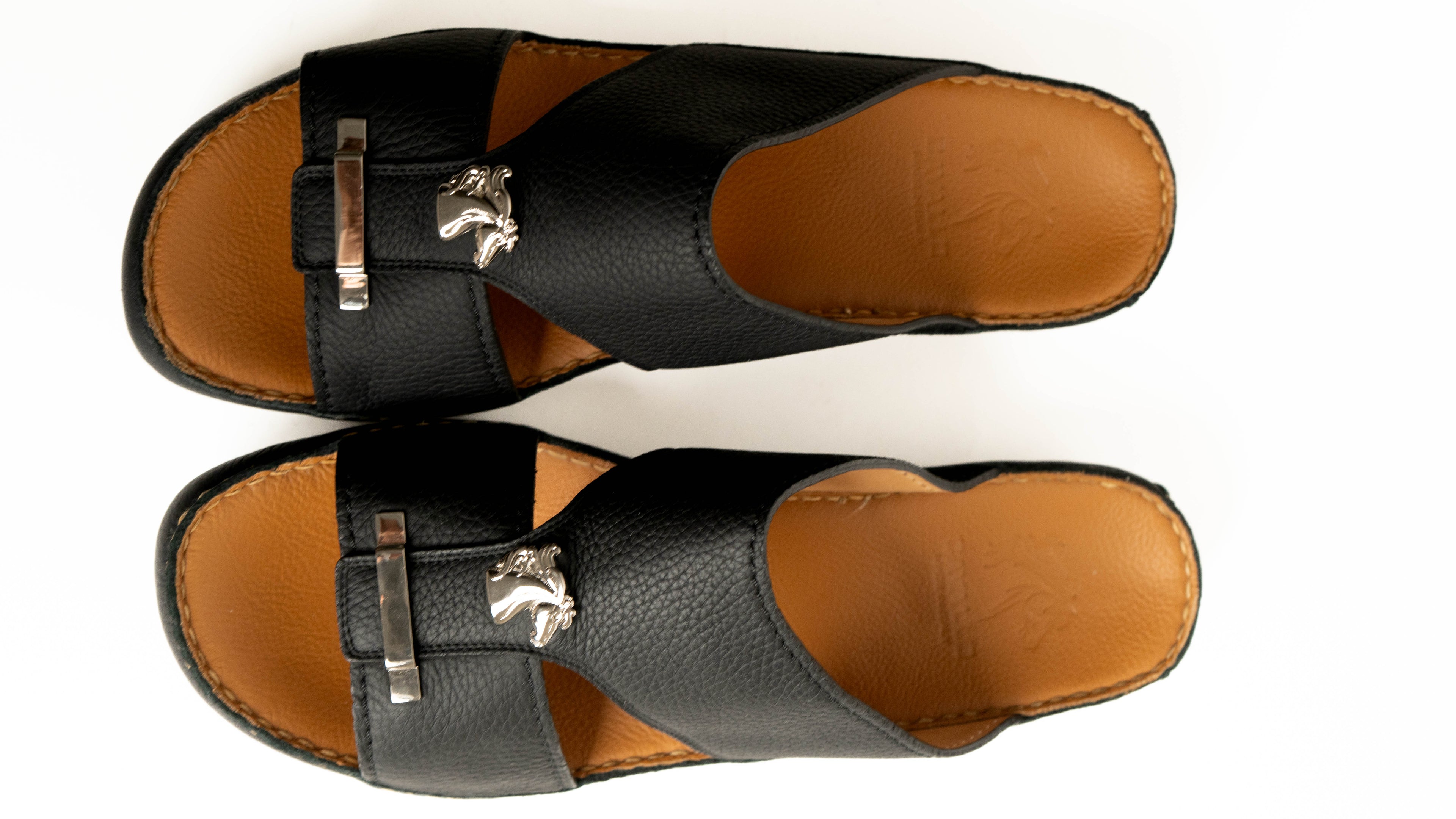 Pair of black sandals with brown soles on a white background