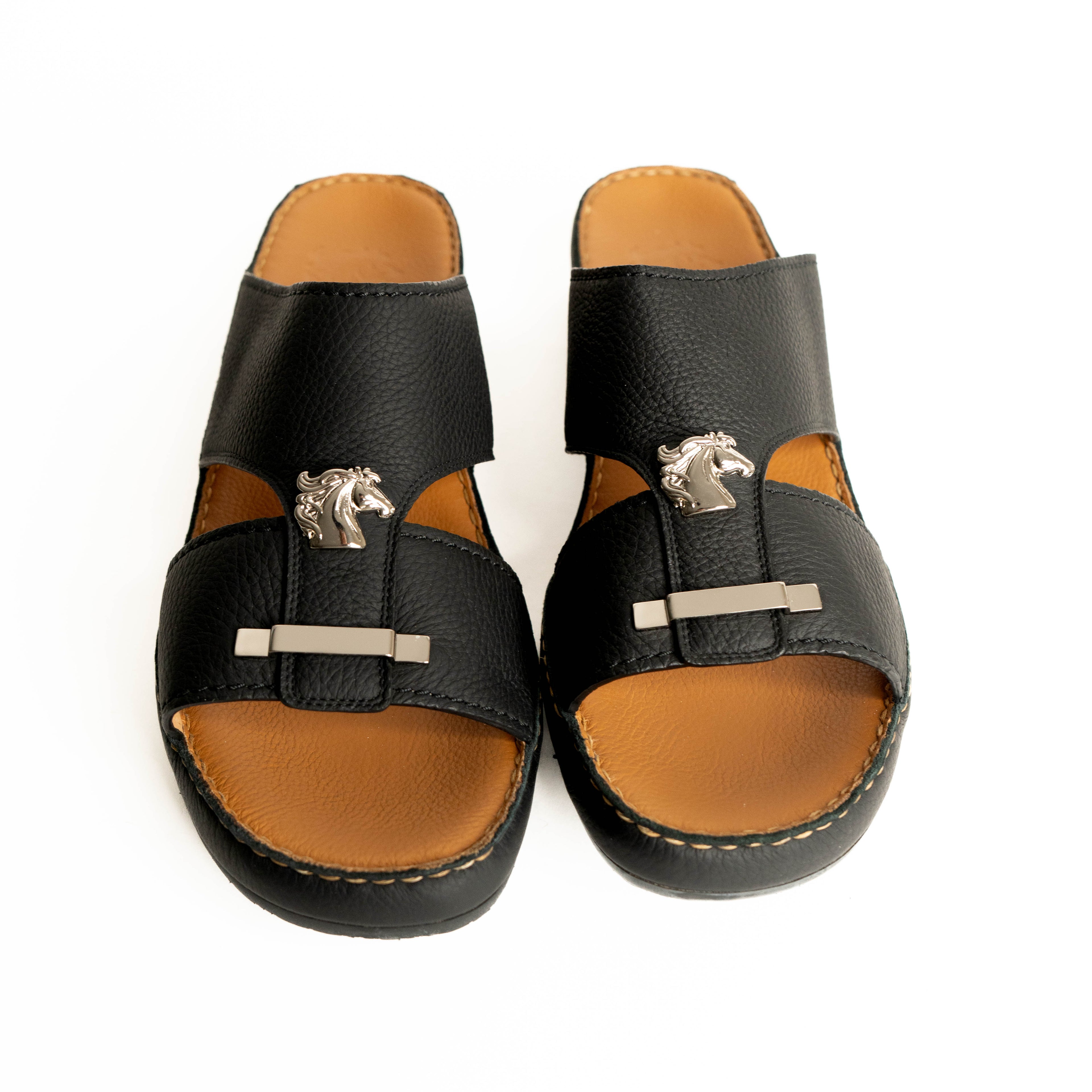 Pair of black and brown sandals with horse buckle design on a white background