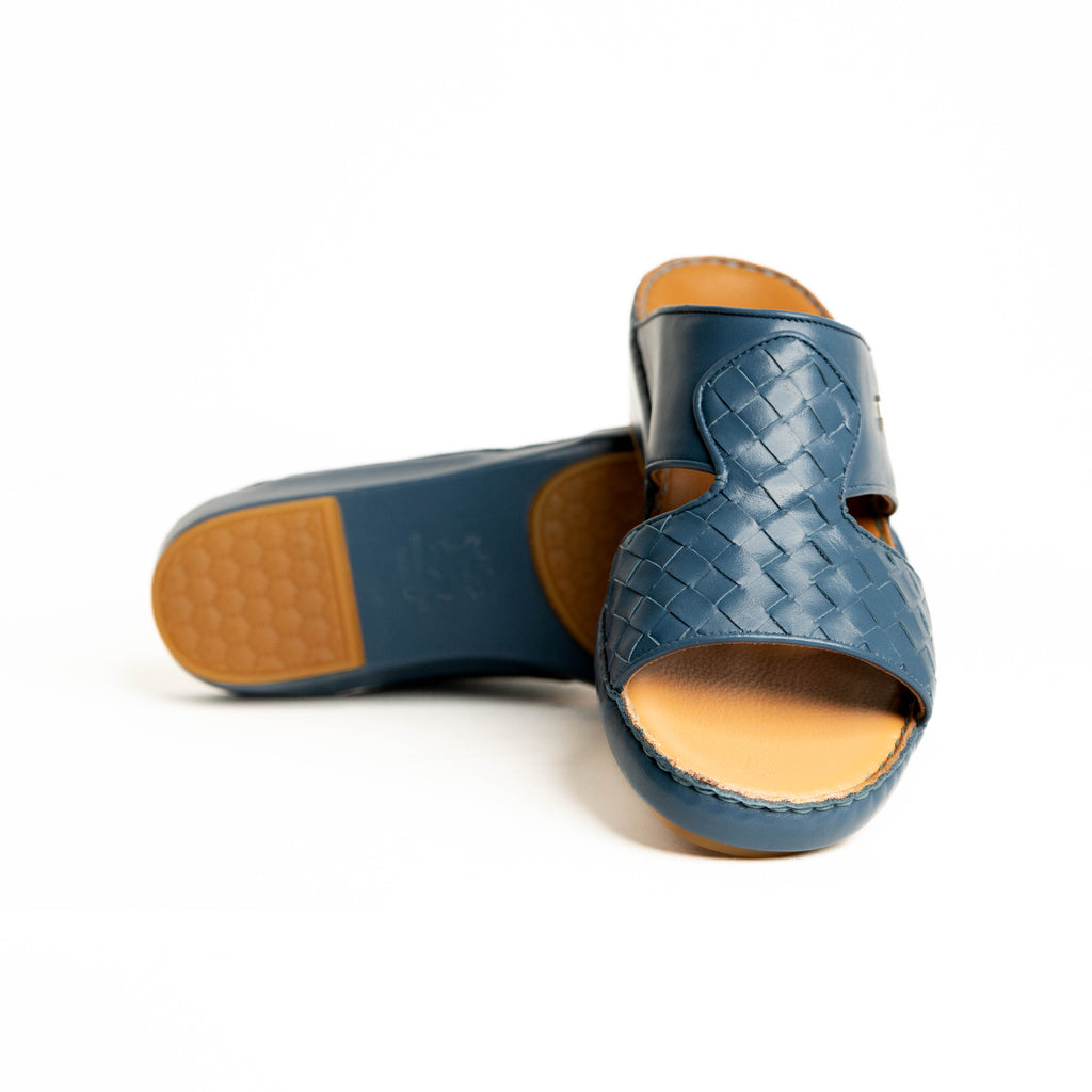 Blue woven sandal with tan sole on a white background