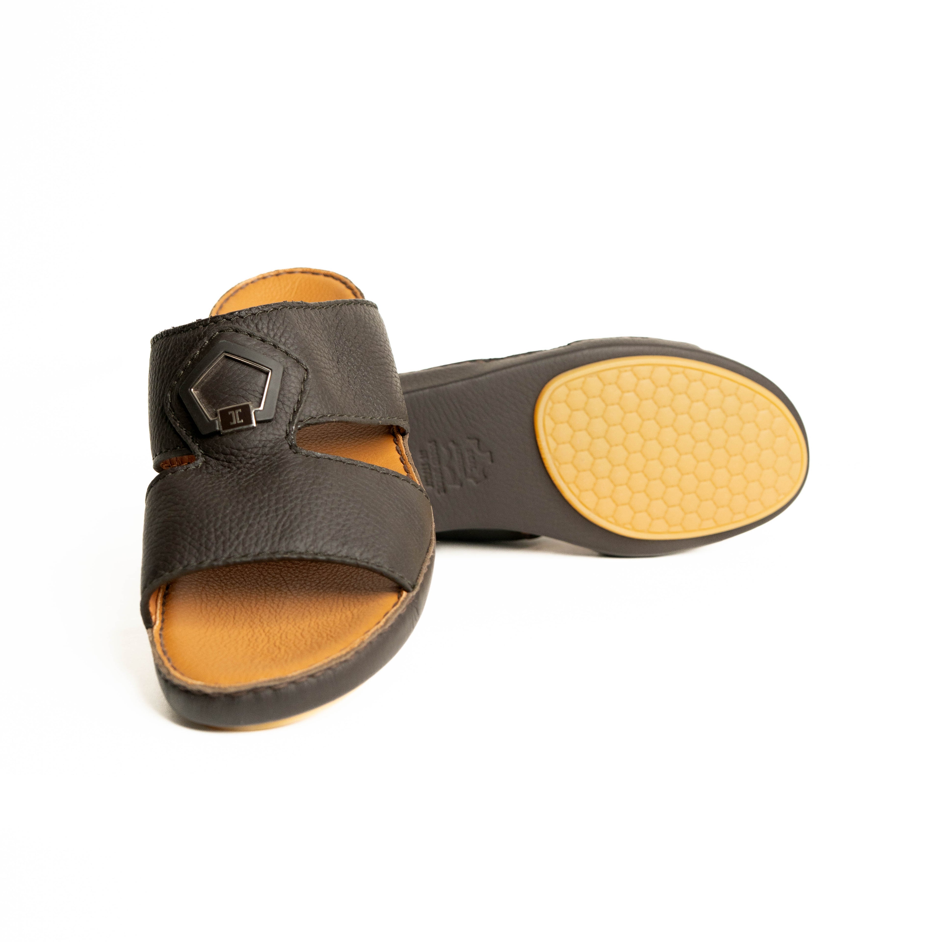 Pair of black sandals with tan soles on a white background