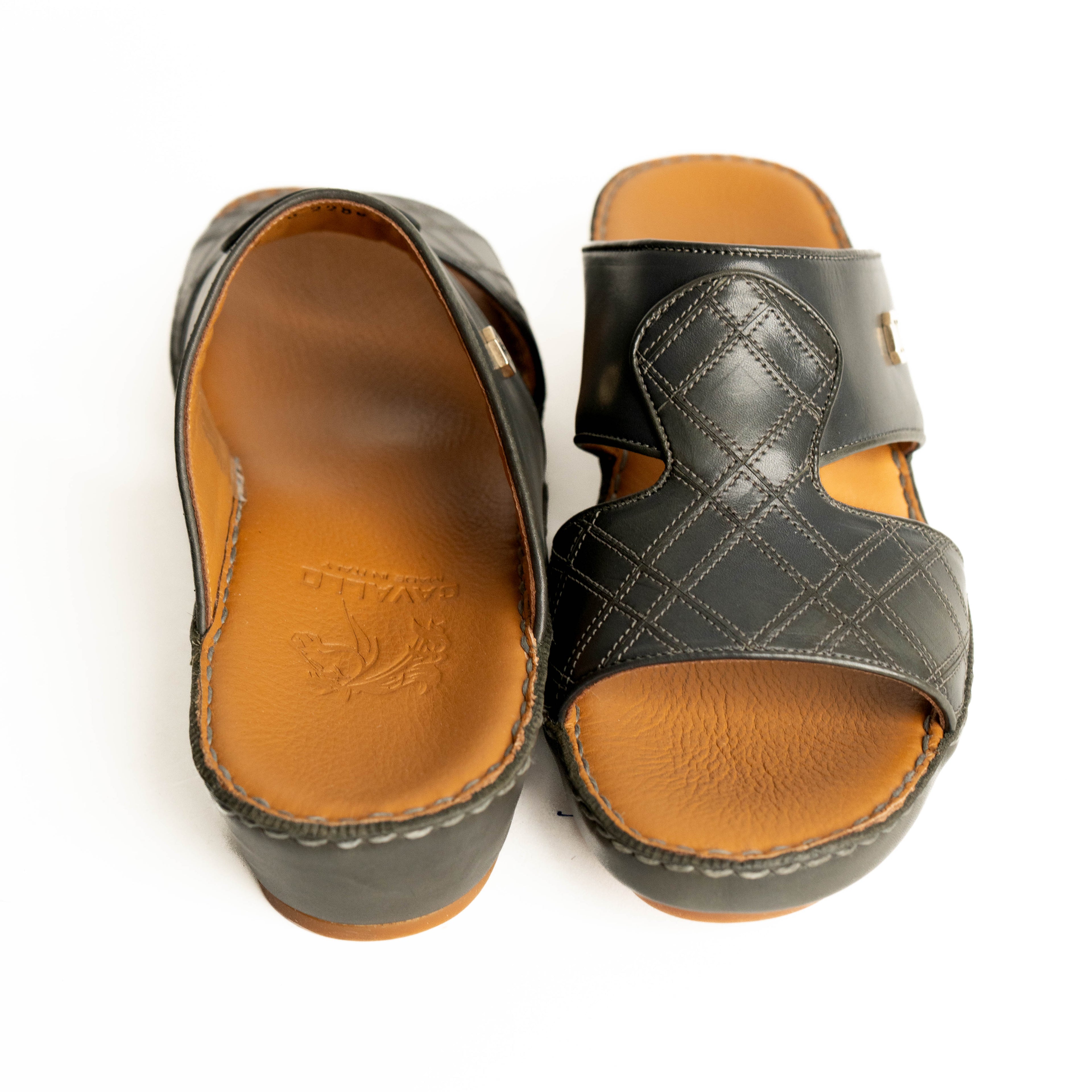 Pair of black sandals with brown soles on a white background