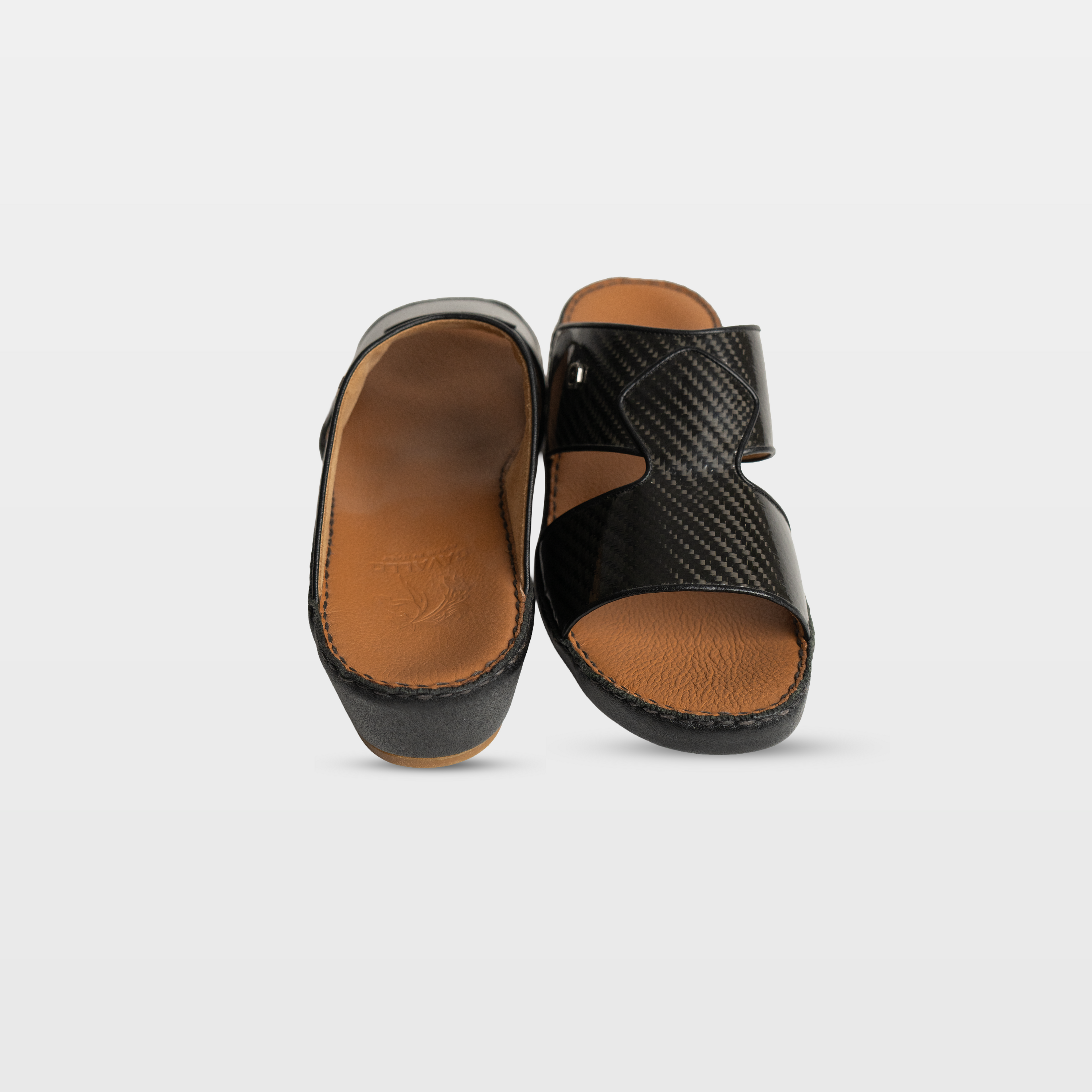 Pair of black sandals with brown soles on a light gray background