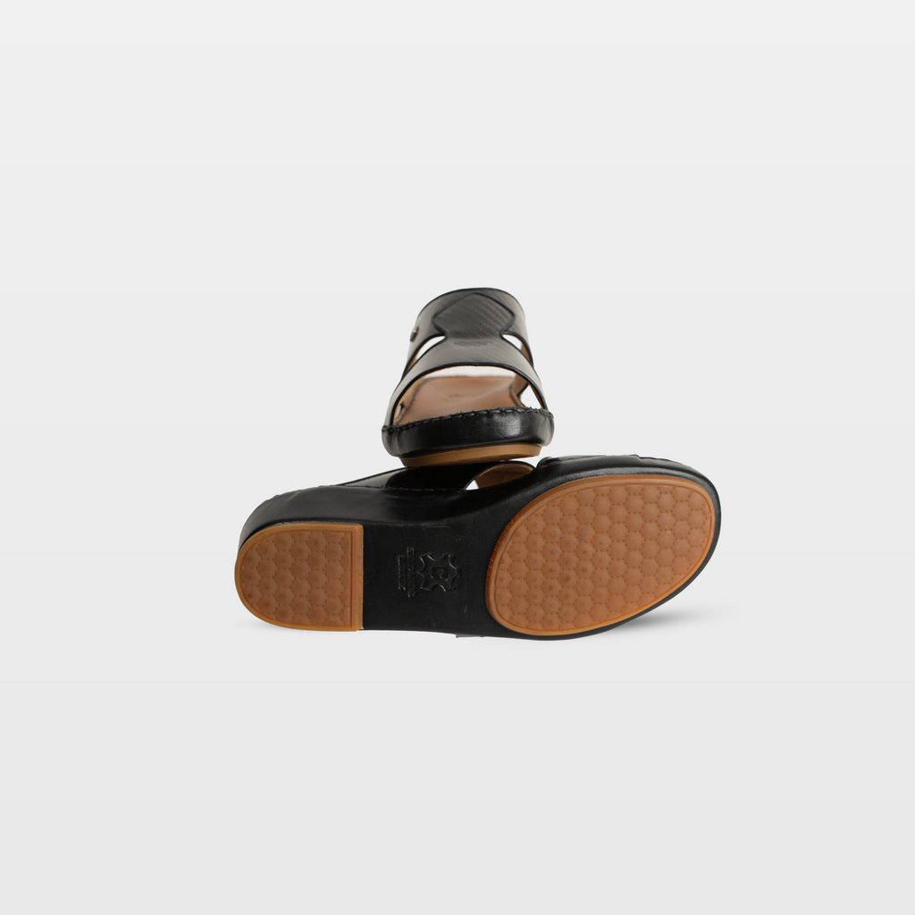 Black sandal with brown sole on a light gray background